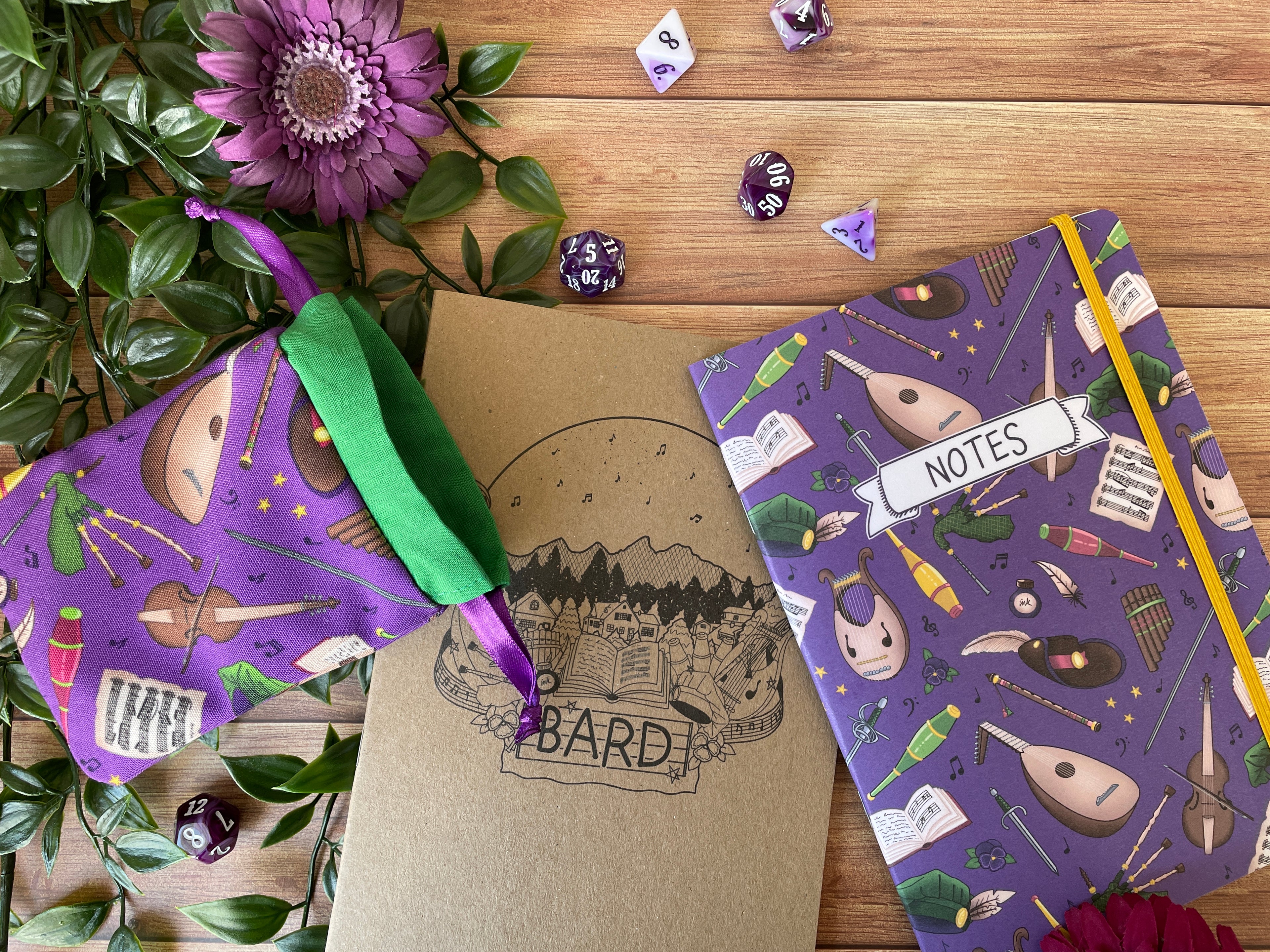 Image features books and dice bags from our bard collection which is designed for music lovers and entertainers. The design features musical instruments, hats, weapons and juggling pins in shades of browns, greens and yellows on a purple background.